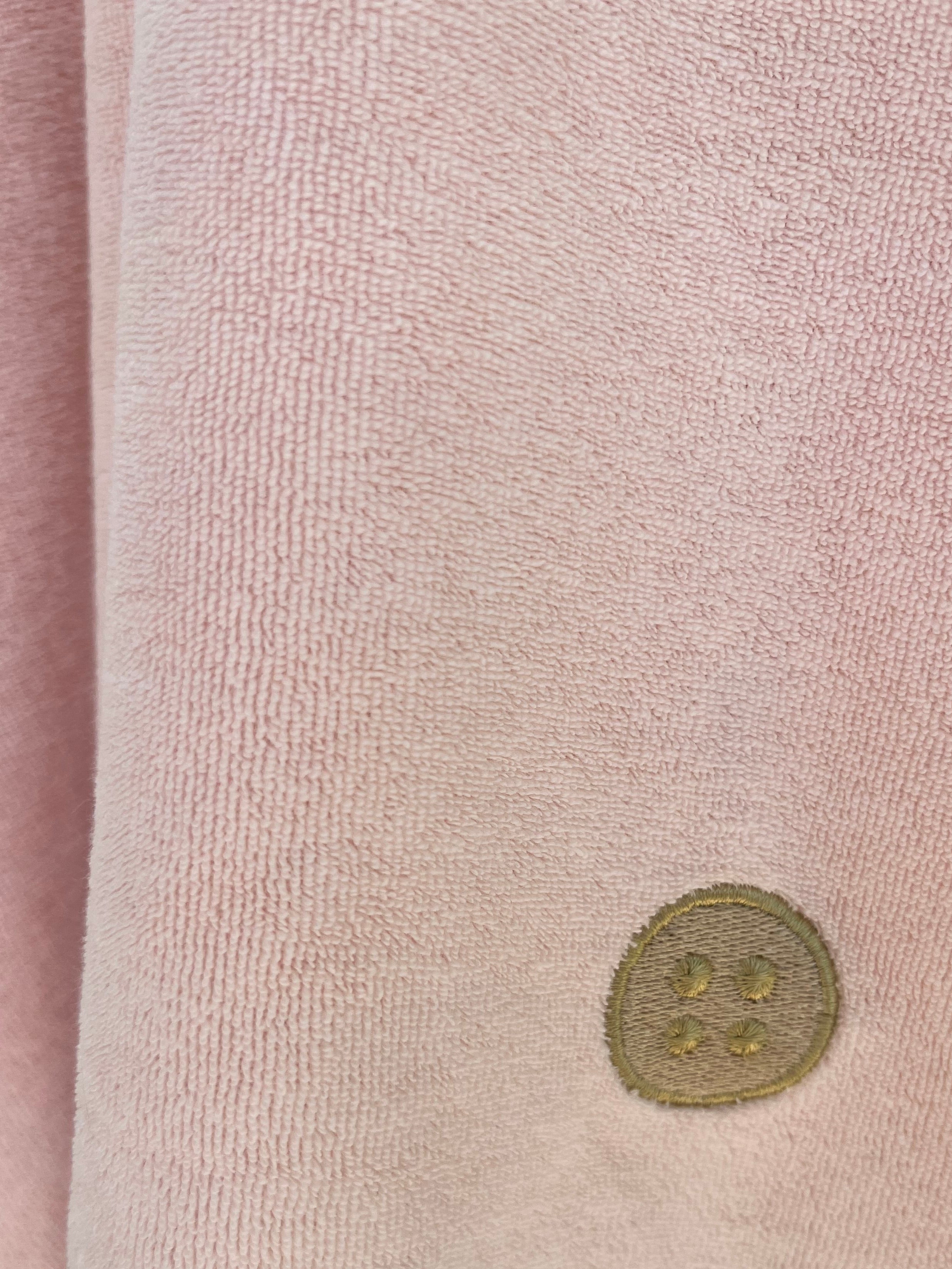 Close-up of soft pink terry toweling fabric with embroidered Dry Dolly logo, showcasing premium quality and attention to detail